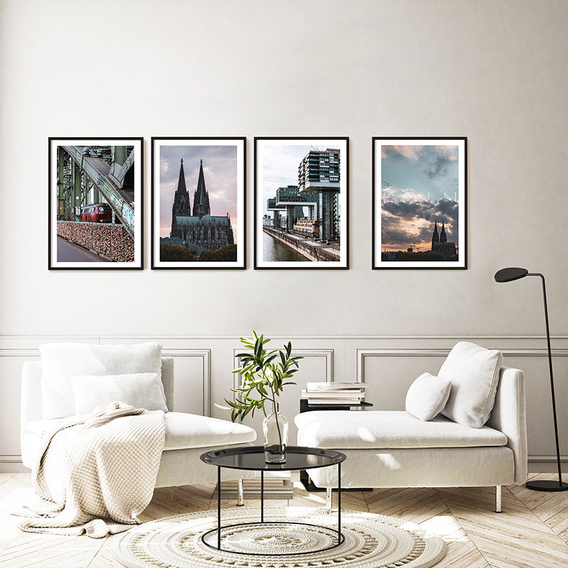 4er Köln Poster Set in reihe im Wohnzimmer über einem grauen Sofa gehangen. Motive vom Kölner Dom, Hohenzollernbrücke und Kranhäusern.