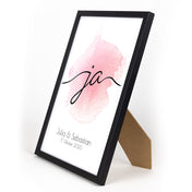 Ja Schriftzug, rosa Hintergrund auf weißem Grund. Unten personalisierte Vornamen & Datum. Bild im Din A4 Rahmen.