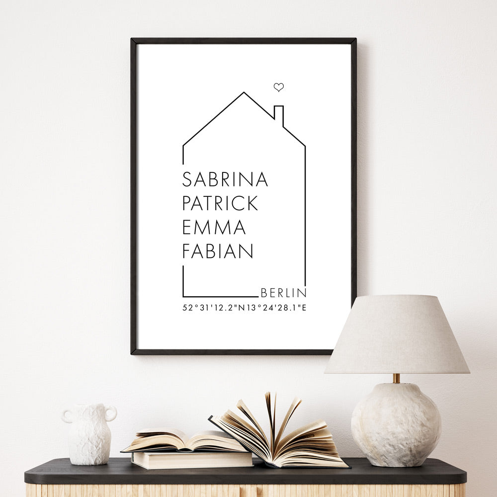 Personalisiertes Haus Familienposter mit individuellen Namen, Ort und Koordinaten. Gerahmt in einem schwarzen Bilderrahmen über der Kommode.