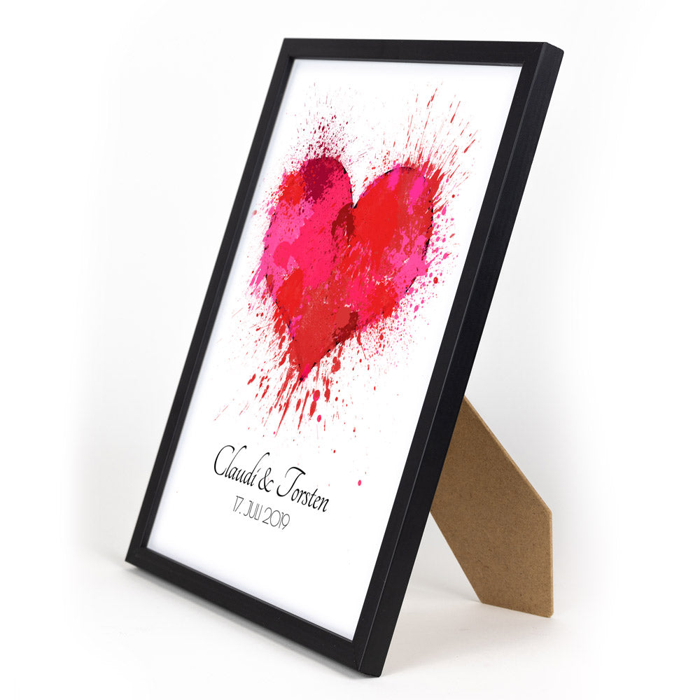 Rotes Herz Poster mit personalisierten Namen und Datum darunter. Bild im schwarzem Din A4 Bilderrahmen mit Aufsteller.