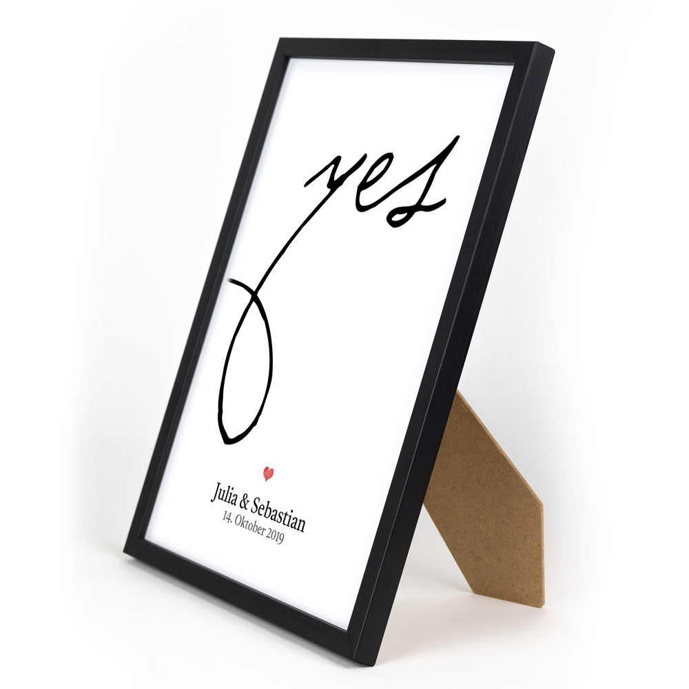 Personalisiertes Hochzeit Poster. Großes Yes in schwarz, darunter ein rotes Herz mit individuellen Namen und Datum. Bild im Din A4 Rahmen.