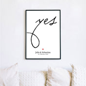 Personalisiertes Hochzeit Poster. Großes Yes in schwarz, darunter ein rotes Herz mit individuellen Namen und Datum. Bild im Rahmen an der Wand.
