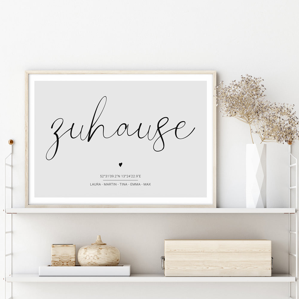 Personalisiertes Poster im Regal im Holzbilderrahmen. Zuhause Schriftzug auf grauem Hintergrund. Individuelle Koordinaten und Vornamen darunter.