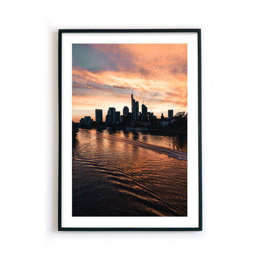 Frankfurt Poster vom Main und der Frankfurter Skyline, mit rotem Himmel beim Sonnenuntergang. Bild mit weißen umlaufenden Rand. Poster fertig gerahmt.