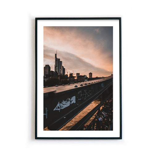 Frankfurt Poster vom Eisernen Steg zum Sonnenuntergang. Frankfurter Skyline im Hintergrund. Bild mit großem weißen umlaufenden Rand. Bild im schwarzen Rahmen.