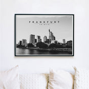 Schwarz Weiß Frankfurt Poster im Querformat. Skyline von Frankfurt am Main. Bild im schwarzen Bilderrahmen an der Wand über eine Sofa.