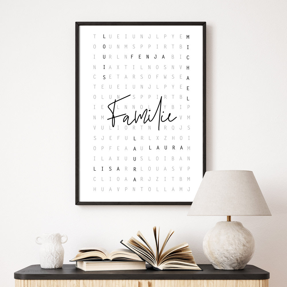 Personalisierbares Poster im schwarzen Bilderrahmen an der Wand. Vornamen sind im Kreuzworträtsel Design eingefügt, in der Mitte steht Familie.