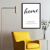 Personalisiertes home Poster mit Familiennamen und Koordinaten. Bild im schwarzen Bilderrahmen an der Wand über einen Sessel.