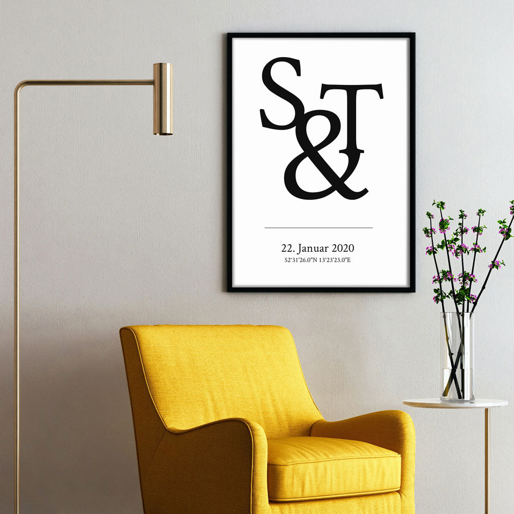 & Zeichen mit individuellen Initialen. Darunter personalisierte Koordinaten und Datum. Poster im schwarzen Rahmen an der Wand.