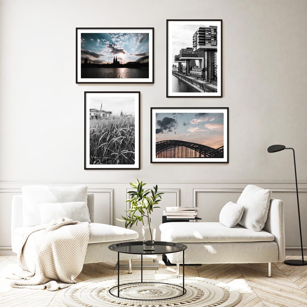 Vier Köln Poster im Querformat in Bilderrahmen über dem Sofa. Kölner Skyline zum Sonnenuntergang. Motive von Gräsern am Rhein, Hohenzollernbrücke, Kölner Dom und Kranhäuser. 