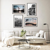 Vier Köln Poster im Querformat in Bilderrahmen über dem Sofa. Kölner Skyline zum Sonnenuntergang. Motive von Gräsern am Rhein, Hohenzollernbrücke, Kölner Dom und Kranhäuser. 