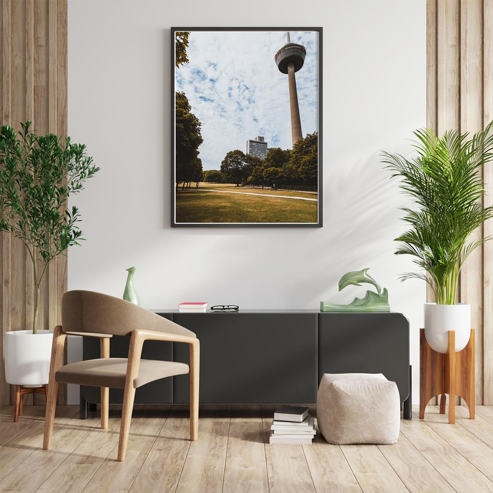 Retro Köln Poster vom Fernsehturm im grünen Gürtel. Grüne Wiese und Bäume im Vordergrund bei blauem bewölkten Himmel. Bild an der Wand im Wohnzimmer.