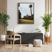 Retro Köln Poster vom Fernsehturm im grünen Gürtel. Grüne Wiese und Bäume im Vordergrund bei blauem bewölkten Himmel. Bild an der Wand im Wohnzimmer.