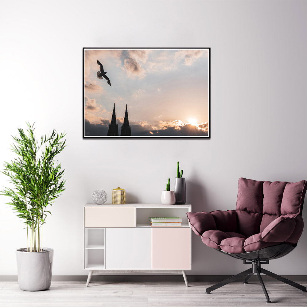 Möwe über den Türmen vom Kölner Dom. Die letzten Sonnenstrahlen hinter dem bewölkten Himmel. Poster im Querformat an der Wand im Wohnzimmer.