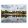 Köln Bild im Querformat. Motiv ist der Fernsehturm, eine Brücke und Bäume, die sich im See spiegeln. Sommertag mit blauem Himmel.