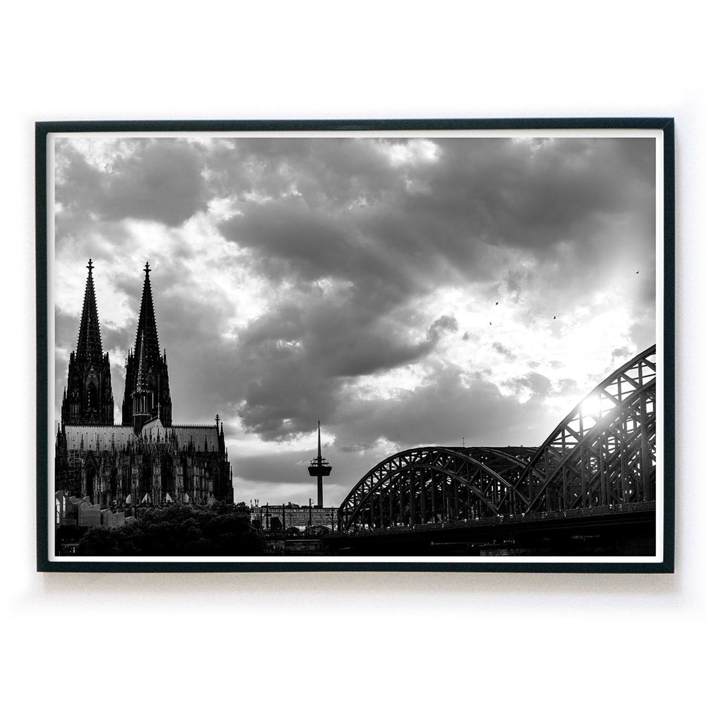 Schwarz Weiß Köln Poster in Querformat und schwarzen Rahmen. Sonnenuntergang bei wolkigen Himmel über dem Kölner Dom, Hohenzollernbrücke oder dem Fernsehturm.