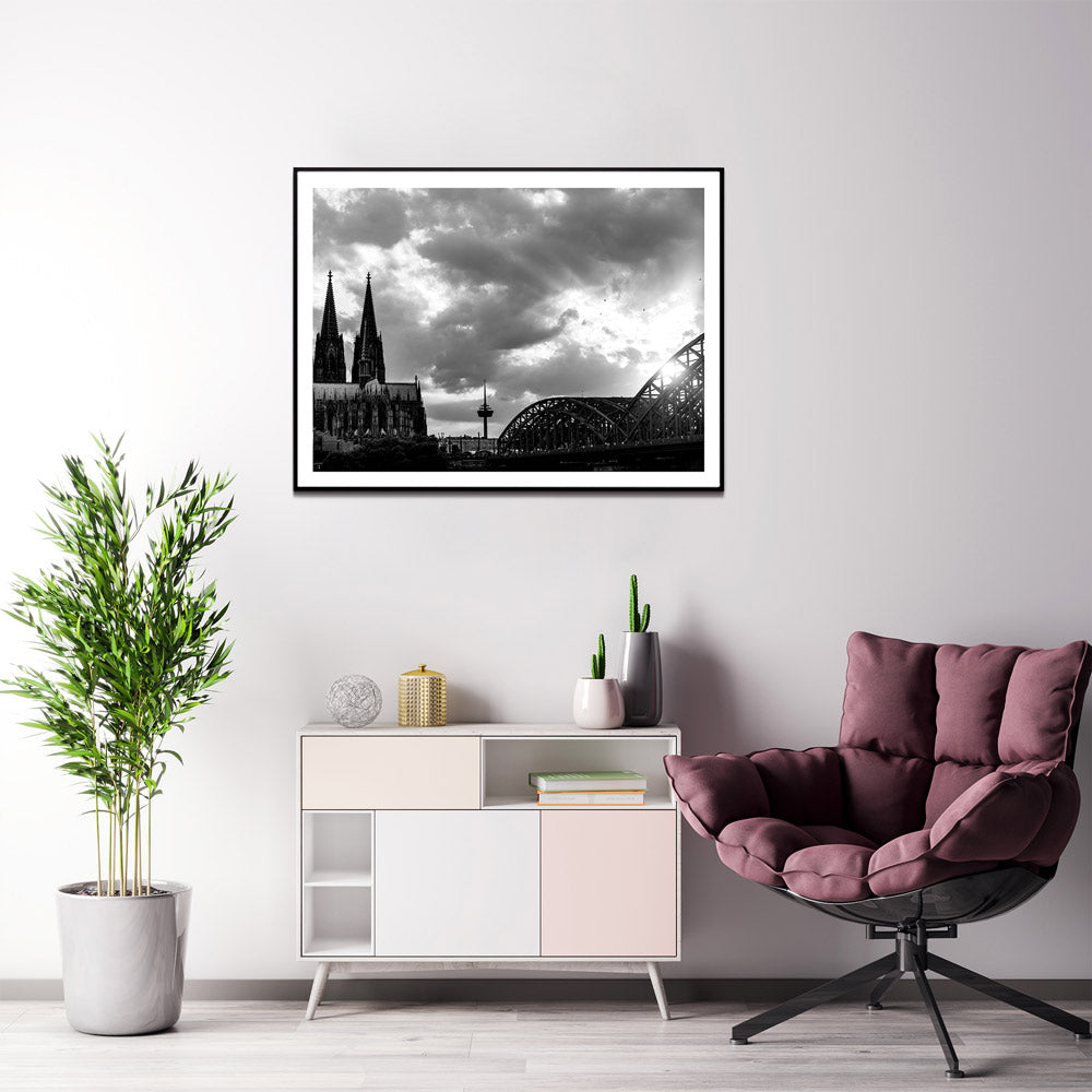 Schwarz Weiß Köln Poster im Querformat. Sonnenuntergang bei wolkigen Himmel über dem Kölner Dom, Hohenzollernbrücke oder dem Fernsehturm. Bild mit weißen Rand fertig gerahmt im Wohnzimmer.