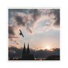 Quadratisches Köln Poster vom Sonnenuntergang über dem Kölner Dom. Über dem Dom fliegt eine Möwe. Kraftvoller blauer Himmel mit Wolken und Sonnenstrahlen.
