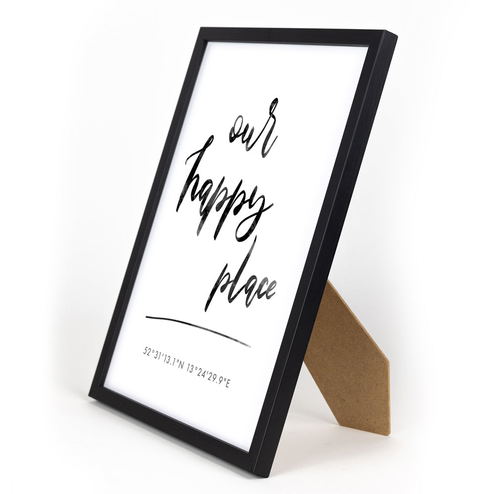 our happy place poster mit individuellen Koordinaten. Im schwarzen Din A4 Bilderrahmen mit Aufsteller.